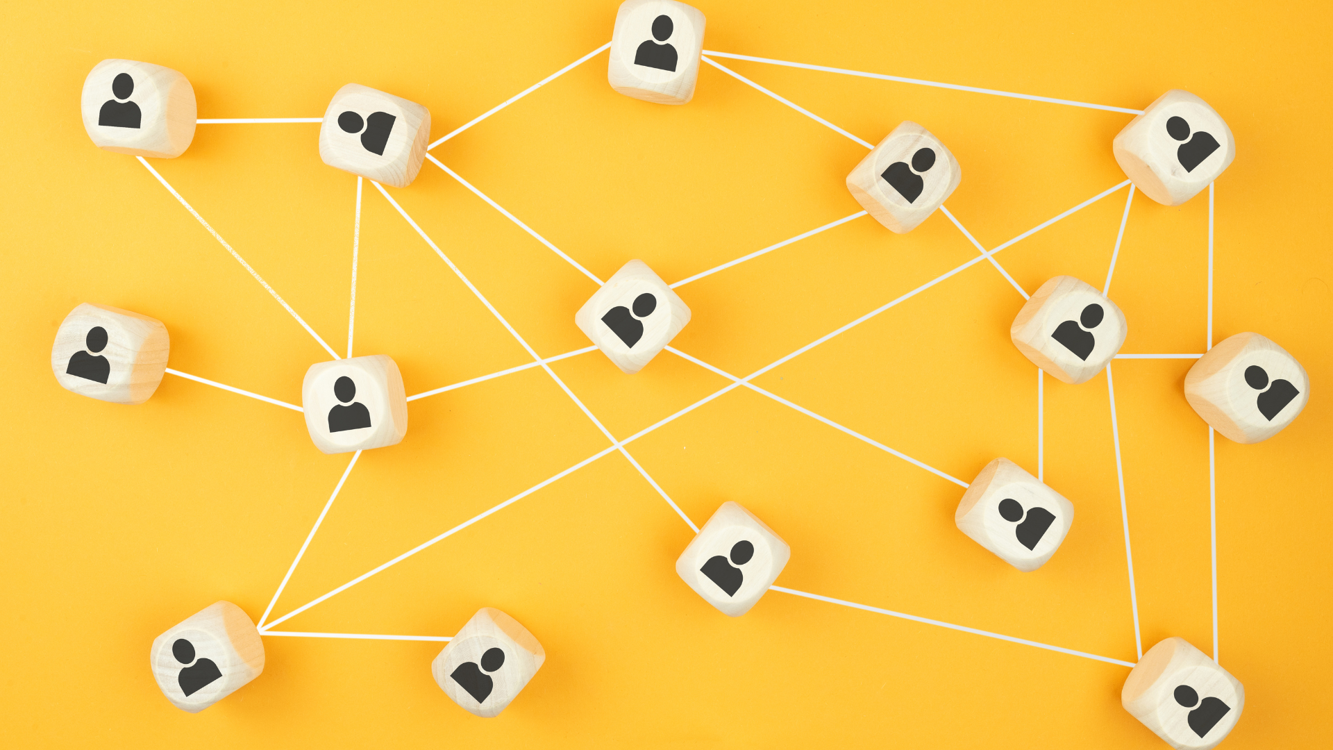 Small wooden blocks with a person icon on a yellow background all connected by string.